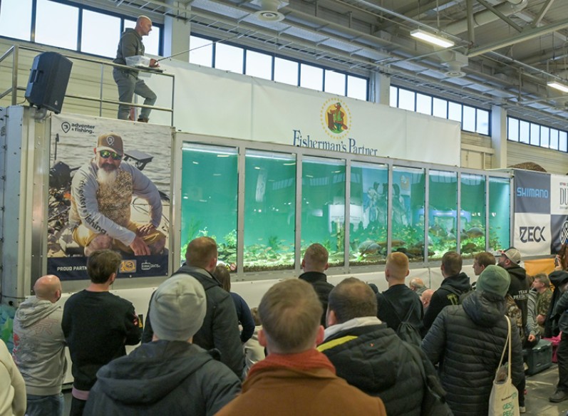 Ein Angler steht auf einem Podest und schaut von oben in ein Aquarium 