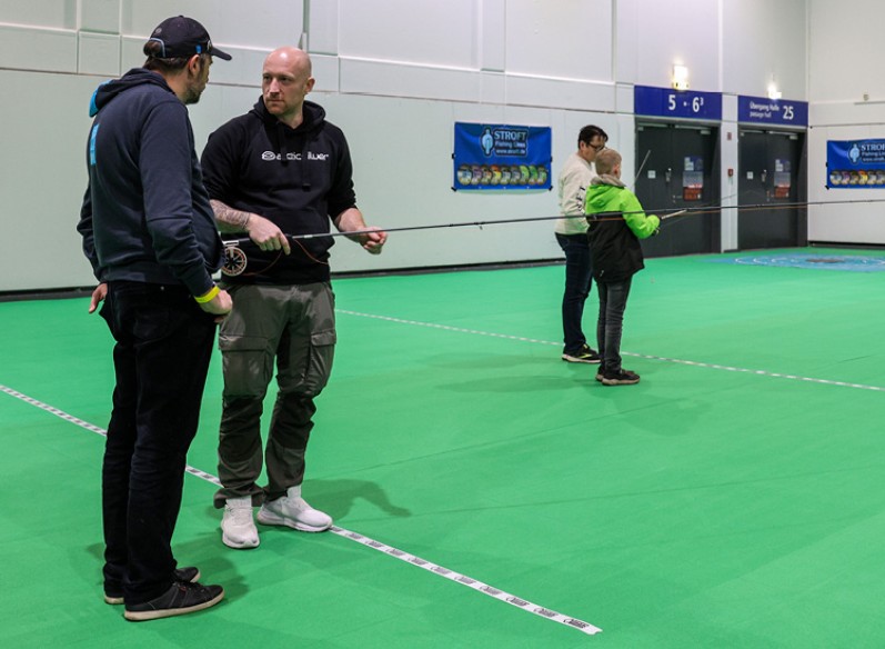 Zwei Personen unterhalten sich, die eine hält eine Angel in der Hand 