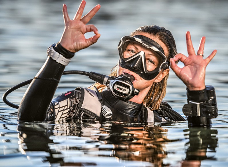 Taucherin im Wasser zeigt Handzeichen