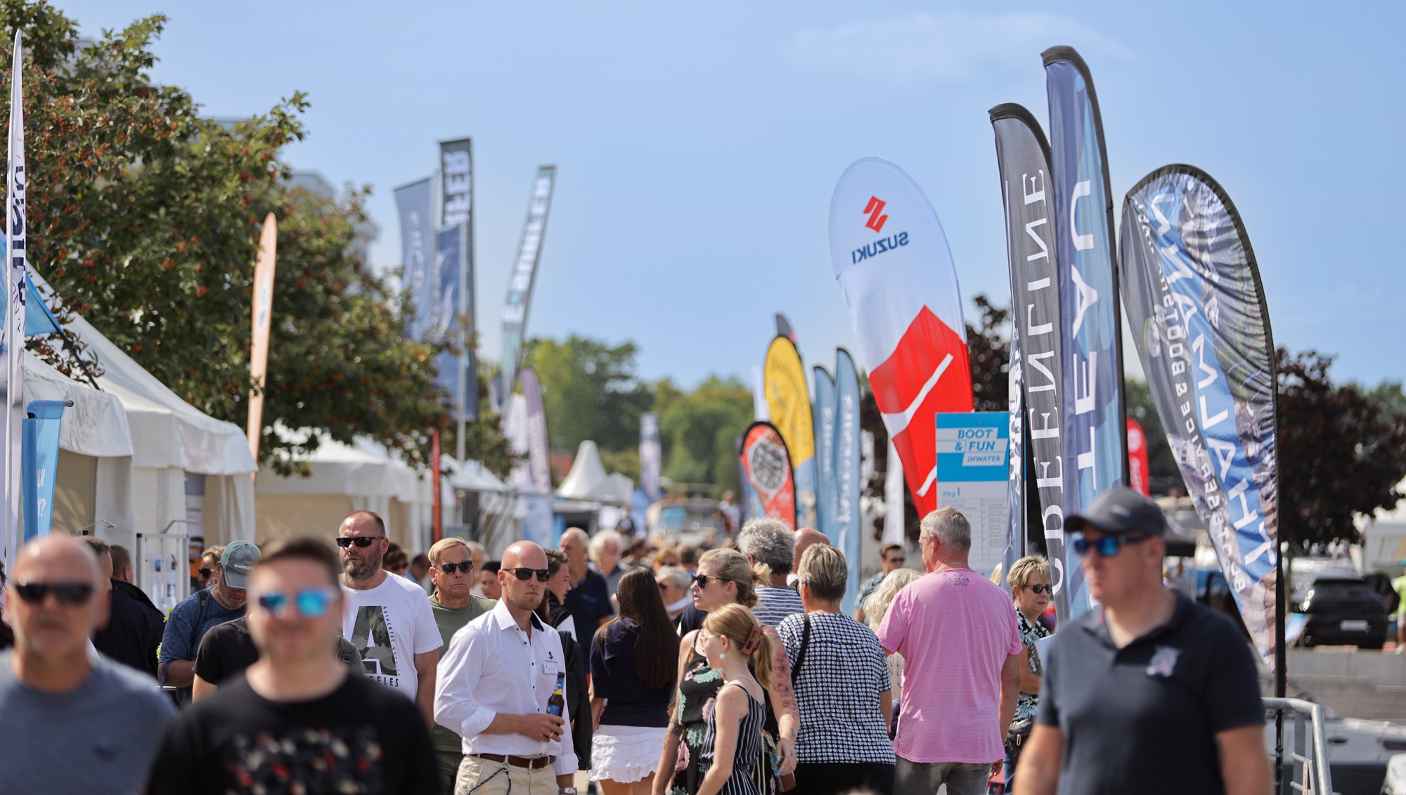 Zwischen Verkaufspagoden, Beachflags und Booten an Stegen: Zahlreiche Besucherinnen und Besucher der BOOT & FUN INWATER 2024 schlendern bei bestem Wetter über die Hafenpromenade der Marina Havelauen. Zwischen Verkaufspagoden, Beachflags und Booten an Stegen: Zahlreiche Besucherinnen und Besucher der BOOT & FUN INWATER 2024 schlendern bei bestem Wetter über die Hafenpromenade der Marina Havelauen.
