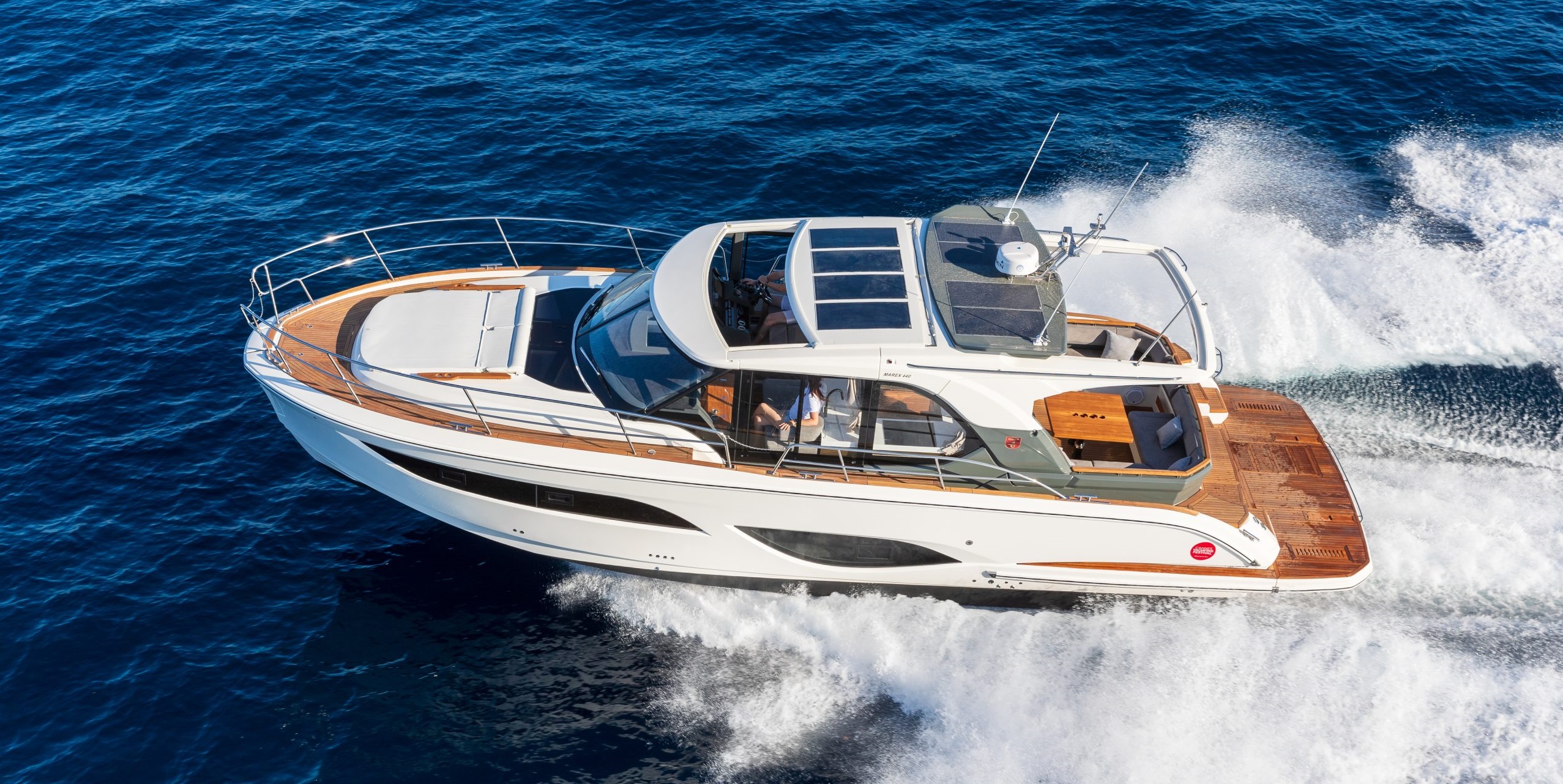 The Marex 440 GC motorboat – a sporty 44-foot yacht from the Norwegian shipyard – is sailing across the sea at high speed. To the right and left of the boat, the water is splashing.