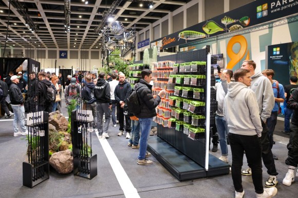 Interessierte Messebesucher an einem Stand mit Angelausrüstung.