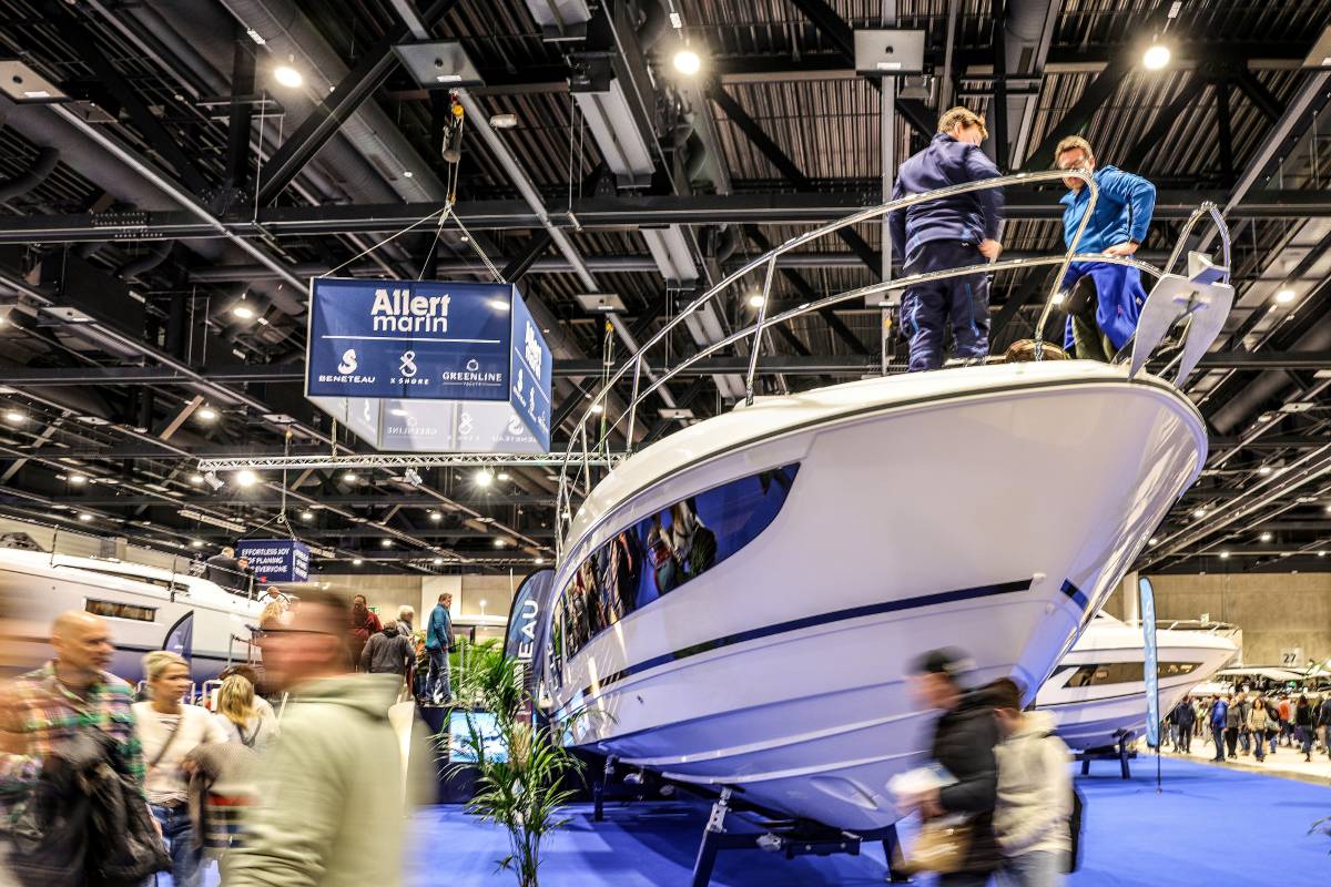 A yacht in the foreground, surrounded by an audience in an exhibition hall.
